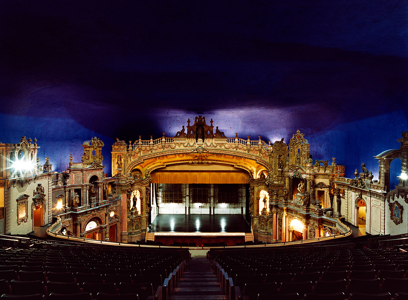 A wide view of the auditorium, with its illuminated stage and deep blue ceiling.