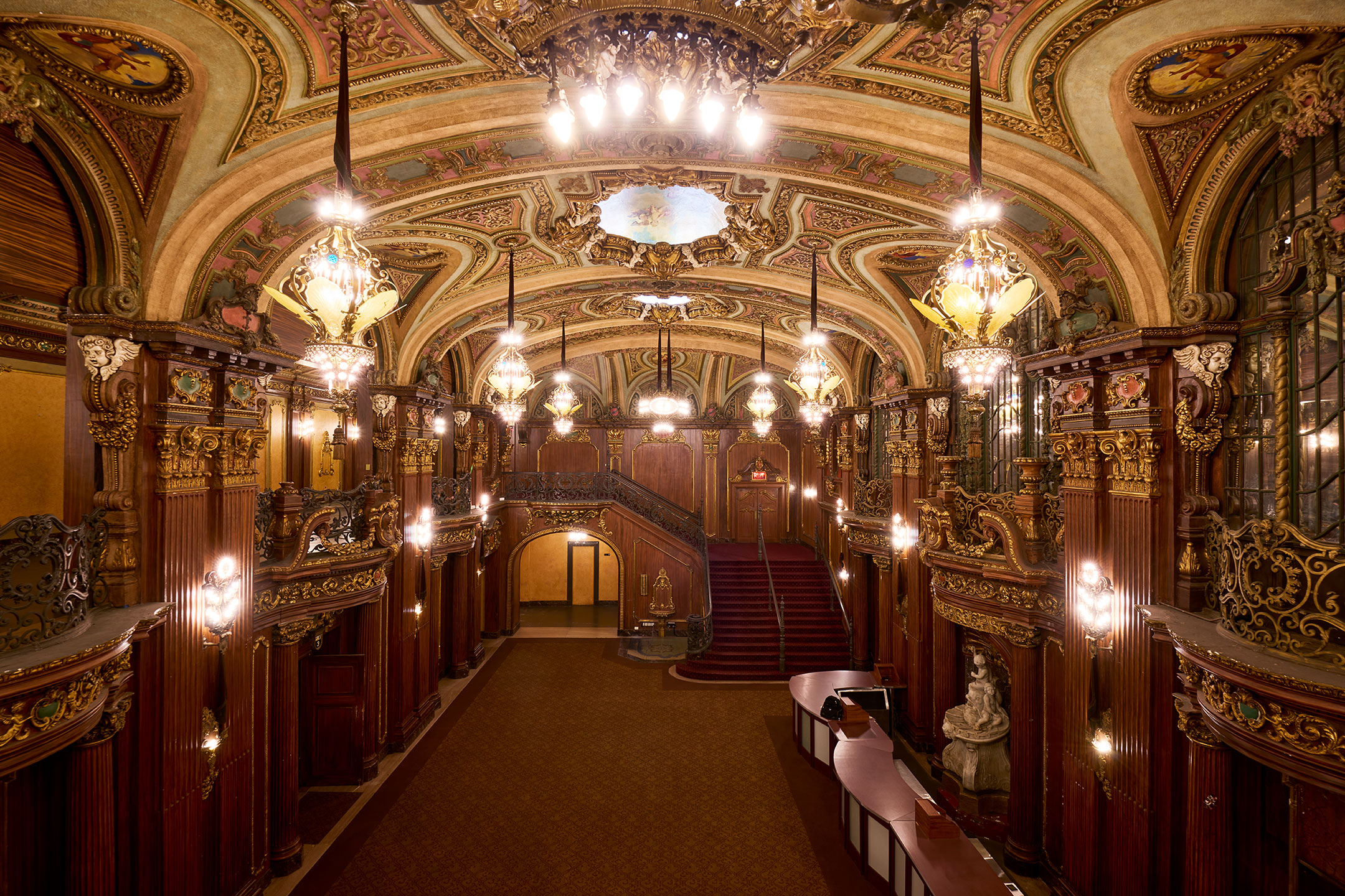 The Paradise's grand lobby viewed from above, with gilded ceilings, chandeliers, and a sweeping staircase