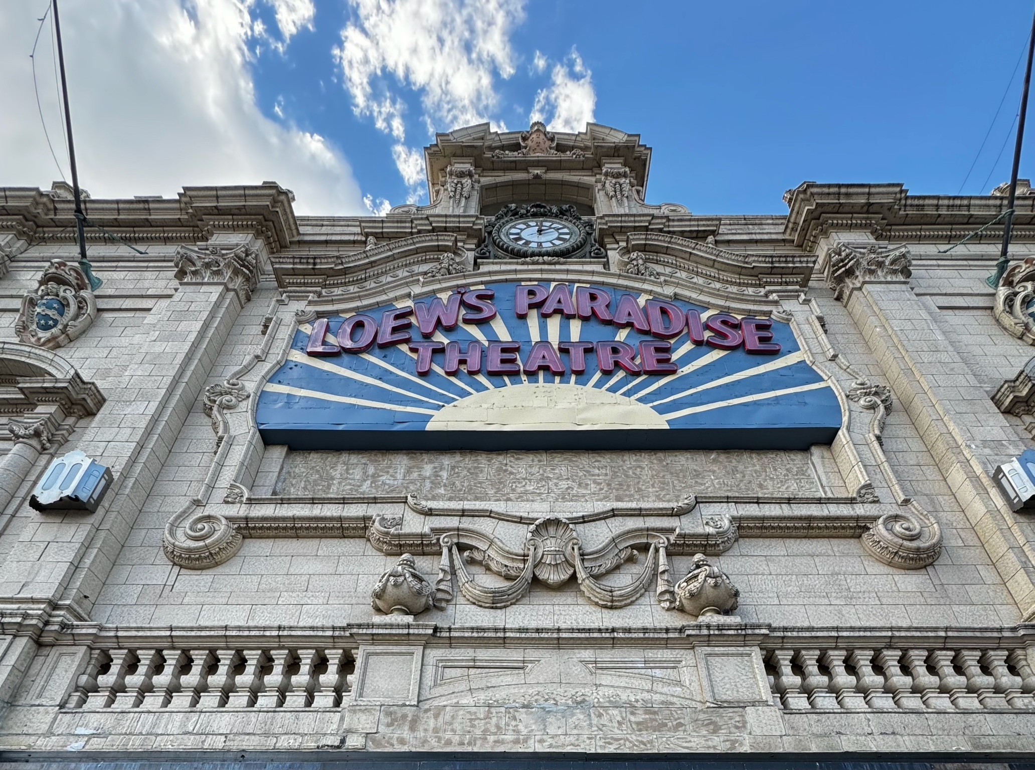 The Loew’s Paradise Theatre sign and ornate stone façade beneath a blue sky on the Grand Concourse